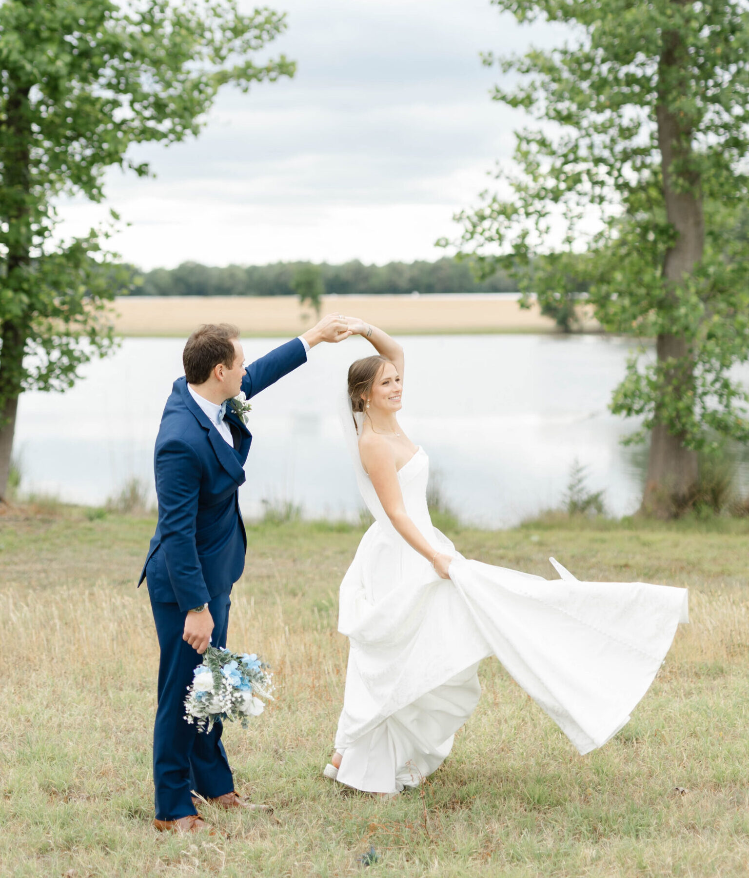BRIDE AND GROOM MARRIED AT WATER'S EDGE AT TART FARMS IN BENSON NC DANCING IN THE FIELD BESIDE POND